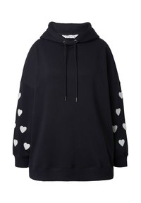 Sudadera negra de tejido suave, con un bolsillo canguro y un cordón en el cuello, decorada con patrones de corazones blancos en las mangas.