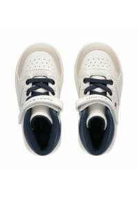 Zapatillas de cuero blancas con acentos en azul marino, puntera perforada y correa ajustable de Velcro. El logo de la marca es visible en la correa.