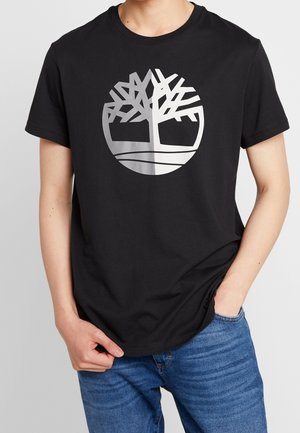 Czarna bawełniana koszulka z srebrnym logo drzewa w kształcie koła, okrągłym dekoltem, krótkimi rękawami i luźnym krojem.