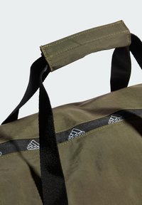 Borsone verde oliva con superficie texturizzata, dotato di spallacci neri e un accento nero con il marchio, caratterizzato da loghi bianchi lungo il bordo superiore.