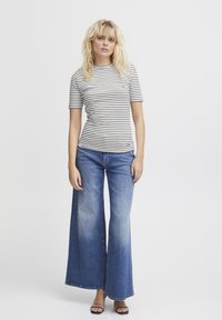 Gestreepte zwart-witte strakke shirt gecombineerd met wijde blauwe denim jeans. De outfit heeft een casual ontwerp met een gladde textuur.