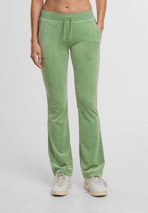 Pantalon en velours vert avec une coupe décontractée, ceinture élastique et cordon de serrage. Possède des poches latérales et une texture lisse et douce.