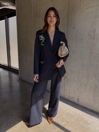 Jūrinio dryžuoto dimso su žaliu gyvačių siuvinėjimu, derančios kelnės ir šviesiai rudos pailgos nosies kulniukai. Laiko šviesiai rudos spalvos rankinę.