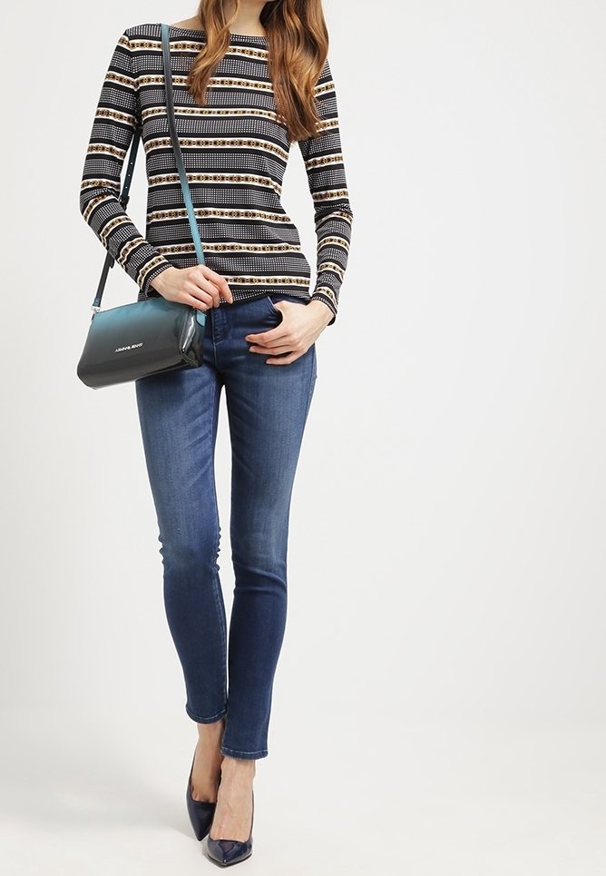 Långärmad randig topp med horisontella mönster, blå tight jeans och marinblå klackar. Axelremsväska i turkos. Slät textur genomgående.