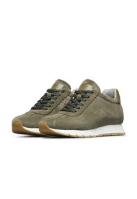 Sneakers in suede verde oliva con lacci neri, suola intermedia bianca e suola esterna in gomma beige. Presentano perforazioni e un design della linguetta ondulato.