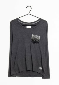 T-shirt gris à manches longues avec un col rond et une poche en sequins présentant un dégradé de motif argent à noir. Étiquette visible à l'ourlet.