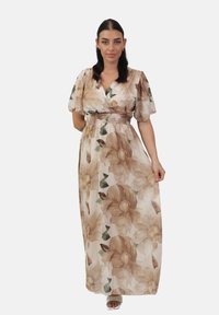 Robe maxi florale en tissu beige transparent, avec de grandes fleurs brunes et des feuilles vertes. Taille élastique et manches volantées.