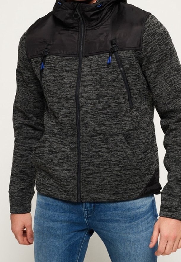 Grå og sort lynlåstrøje med tekstureret stof, med sort hætte, to forlommer og snorede detaljer.