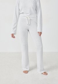 Ensemble de vêtements de détente à rayures comprenant un haut ample à manches longues et un pantalon décontracté en tissu doux blanc et gris clair avec une taille à cordon.
