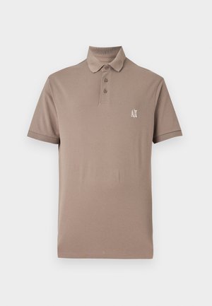 Bēšas krāsas polo krekls, izgatavots no gludas kokvilnas. Iekļauj apkakli, trīs pogu aizdari un mazu baltu logo kreisajā krūtīs. Īsas piedurknes.