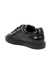 Sneaker nera lucida con tre cinturini in velcro, suola spessa e colletto imbottito, mostrata da un'angolazione laterale posteriore.