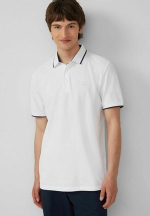 Weißes Polohemd mit einem gerippten marineblauen Kragen und Bündchen, ausgestattet mit drei Knöpfen und einem kleinen Logo auf der linken Brust. Glatte Baumwolltextur.