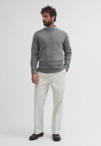 Maglione grigio a maglia, camicia colletto azzurro chiaro sotto, pantaloni beige e scarpe marroni scure. Design semplice con una vestibilità rilassata.
