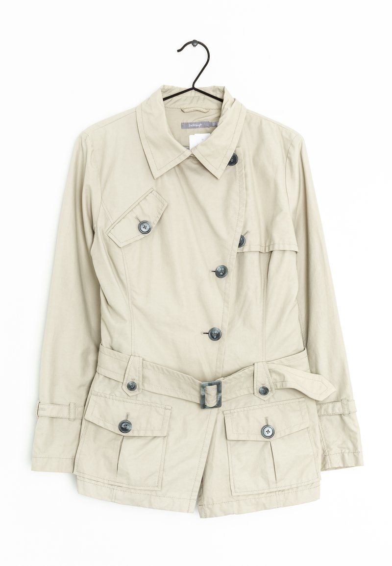 Cappotto corto beige con un design strutturato, dotato di vita regolabile con cintura, quattro tasche frontali e bottoni scuri, appeso a un gancio.