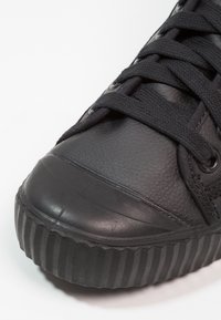 Czarne sneakersy z gładką skórzaną cholewką, teksturowanym czubkiem i płaskimi sznurówkami. Karbowana podeszwa zapewnia przyczepność i trwałość.