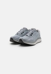 Baskets de sport gris clair avec une tige en maille respirante, motifs texturés, fermeture à lacets, semelle rembourrée et une semelle extérieure en caoutchouc noir contrastant.