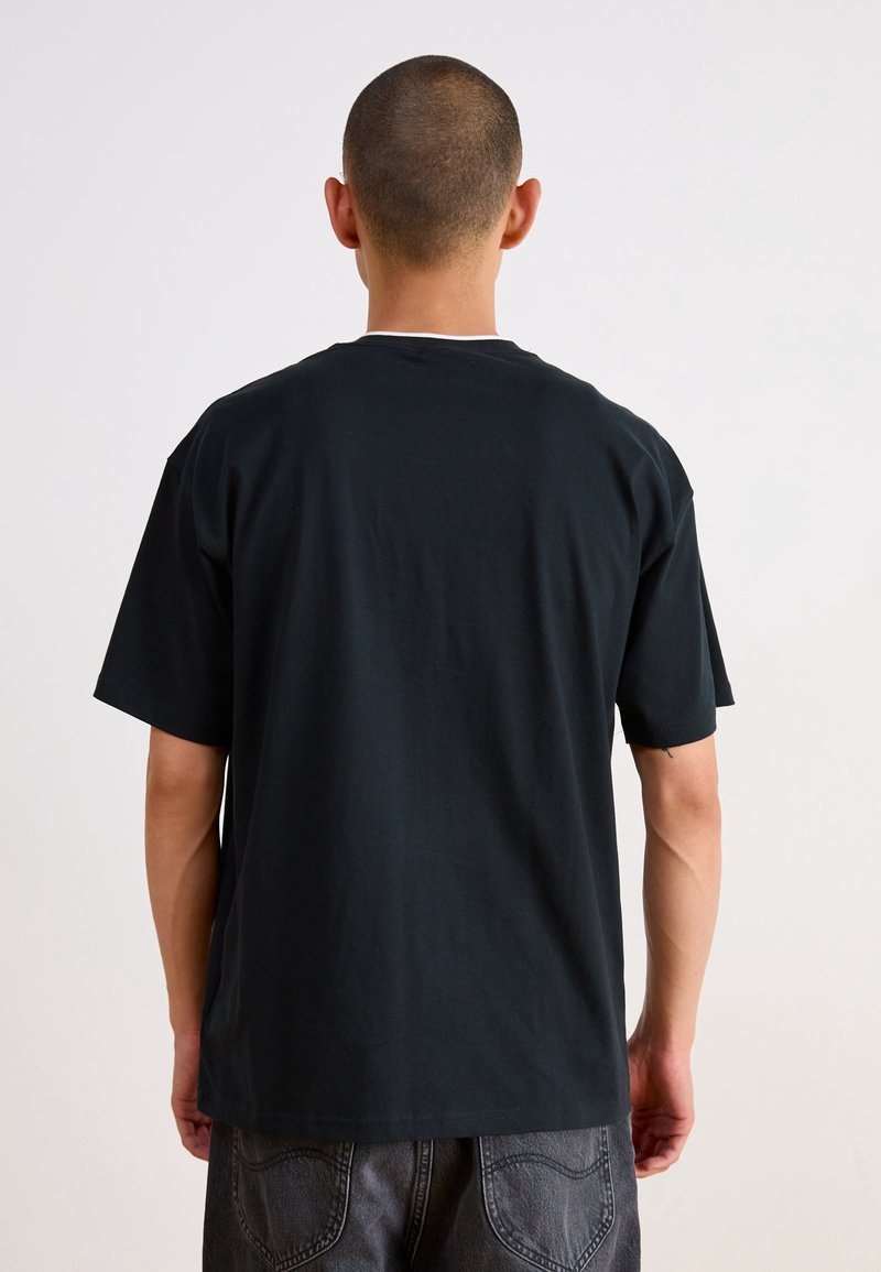T-shirt en coton noir avec une coupe décontractée, des manches courtes et un col rond. Dos uni sans logos ou motifs visibles.