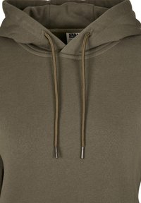 Sweat à capuche vert olive avec cordons et embouts métalliques, présentant une capuche double couche et des coutures visibles sur un tissu doux.