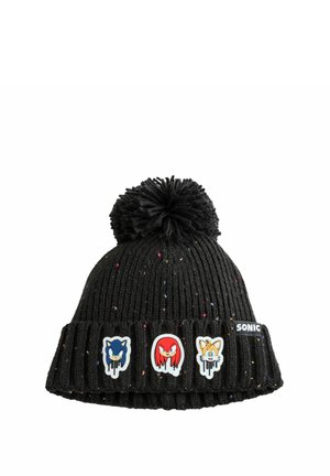 Zwarte gebreide beanie met een pompon bovenop, voorzien van drie kleurrijke karakterpatches en vlekken kleur door de stof.