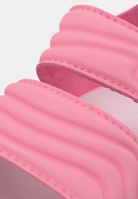 Roze rubberen sandalen met een schuifzool, voorzien van gevormde geribbelde banden en een glad interieur. Het ontwerp benadrukt comfort met een gevoerde zool.