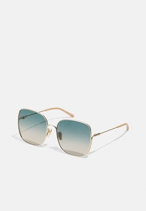 Gold-framed sunglasses with square lenses featuring a gradient tint from blue to beige. Thin, curved arms with textured accents.
