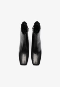 Μαύρες δερμάτινες μπότες στον αστράγαλο με μυτερή μύτη, λεία υφή και κλείσιμο με φερμουάρ στο πλάι. Διαθέτουν κομψό, αεροδυναμικό σχεδιασμό.