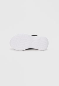Schwarzer Sportschuh mit einer weißen Gummisohle, der über ein strukturiertes Profil für besseren Halt verfügt und ein minimalistisches Design aufweist.