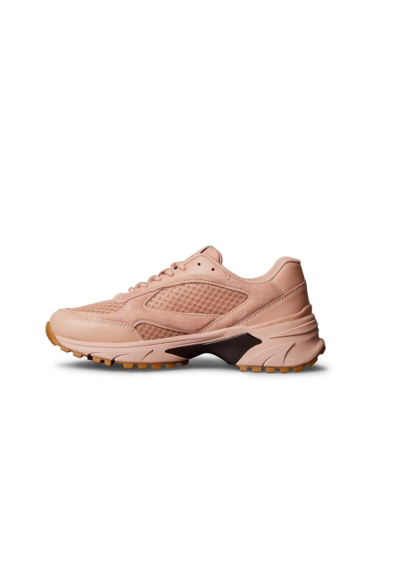 Zapatilla deportiva de color rosa claro con paneles de malla y gamuza, suela gruesa con acento negro y suela exterior de goma color caramelo, vista desde el lado interior.