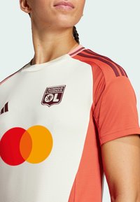 Maillot de soccer rouge et blanc avec un tissu texturé, à manches courtes, et le logo de l'Olympique Lyonnais. Comprend un logo circulaire de Mastercard.