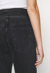 Zwarte denim jeans met een hoge tailleband, voorzien van twee achterzakken en een rechte pijpdesign. De stof heeft een zachte, licht versleten textuur.