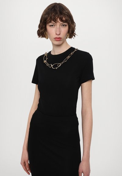 Black short-sleeve top featuring a gold chain necklace with circular elements. Smooth texture, fitted design, and crew neckline.