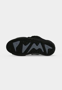 Black sneaker sole with textured grip and large raised letters spelling "PUMA" in dark gray on the bottom.