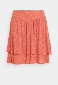 Jupe évasée en tissu corail avec des pois blancs. Elle présente une taille ajustée et des volants superposés pour ajouter de la texture et du mouvement.