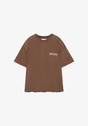 Maglietta oversize marrone con maniche corte e testo rosa "Gilda Season Small, Sweet, and Sassy" sul petto a sinistra.