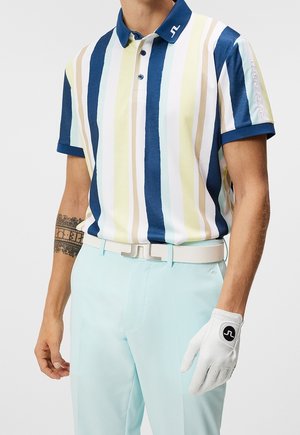 Mann trägt hellblaue Hose, weißen Gürtel, weißen Golfhandschuh und gestreiftes kurzärmeliges Poloshirt mit blauen, weißen, gelben und beigen vertikalen Streifen.