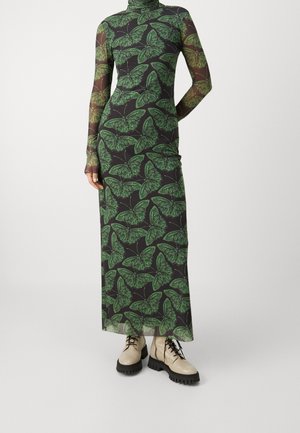 Długa przezroczysta czarna sukienka z zielonym nadrukiem motyli, dopasowany golf i rękawy, zestawiona z beżowymi masywnymi botkami na sznurowadła.