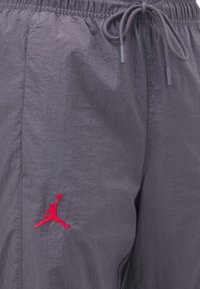 Grå träningsshorts med elastiskt midjeband och dragsko. Har en röd broderad Jumpman-logotyp på vänster framside.
