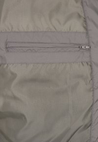 Grått tygpanel med en horisontell stängd dragkedjeficka, som visar detaljerad sömnad och en slät yta.