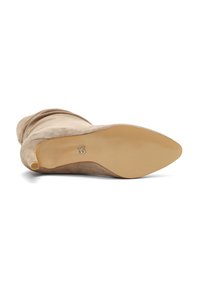 Stivale alto in suede beige, con punta affusolata, texture liscia, forma snella e suola in gomma beige con branding minimale sul fondo.