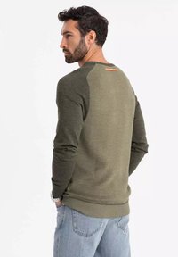 Maglione verde oliva con design a strisce testurizzate sul retro e maniche a tinta unita. Presenta un orlo a coste e un accento arancione vicino al collo.