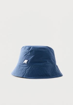 Kék vödörkalap kis fehér és tengerészkék logófolttal az oldalán, a karimán varrott részletekkel.