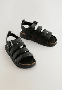 Schwarze Leder-Sandalen mit vier breiten Riemen, strukturierten Oberflächen und einer verstellbaren Schnalle. Korkfußbett und robuste Gummisohle.