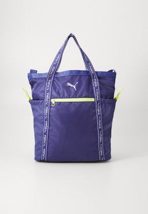 Borsa tote in nylon viola con manici doppi, tasca frontale con zip e dettagli in zip giallo. Presenta il logo Puma sul lato e cinturini a fantasia.