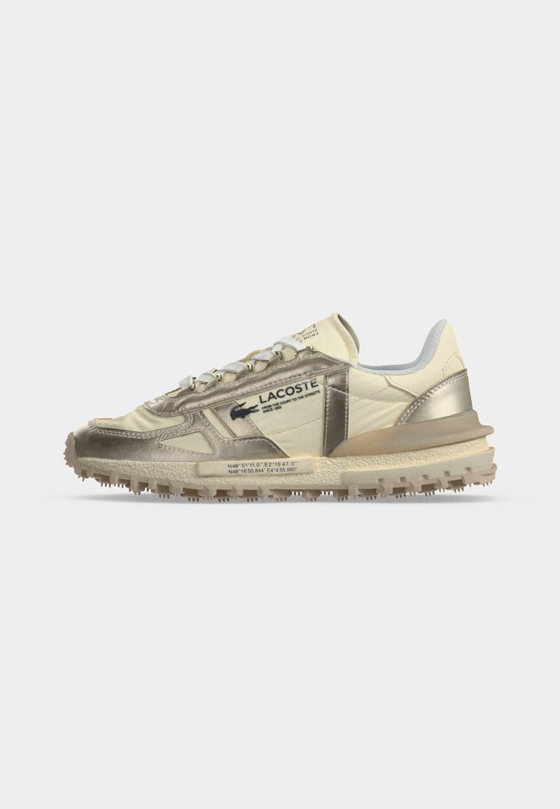Beiger und metallisch goldener Lacoste Sneaker mit strukturierter Sohle, seitlichem Logo und gedruckten Koordinaten auf der Zwischensohle, dargestellt auf weißem Hintergrund.