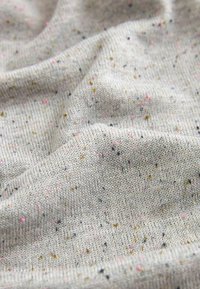 Helles graues Gewebe mit Sprenkeln in Rosa, Blau und Gelb, das einen weichen, strukturierten Strick aufweist und ein lässiges, gemütliches Design vermittelt.