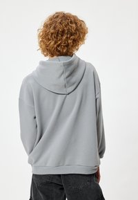 Lichtgrijze hoodie van een zachte katoenmix, met een grote capuchon en geribbelde zoom. Het ontwerp heeft een relaxed fit met verlaagde schouders.