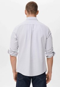 Camisa de manga larga a rayas en gris claro y blanco, con cuello abotonado, mangas remangadas y dobladillo curvado.