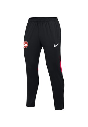 Czarne spodnie sportowe z elastycznym pasem, logo Nike na prawej uda, czerwono-białe okrągłe godło na lewym udzie i czerwone akcenty po bokach.