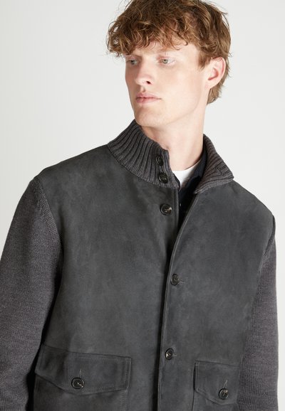 Giacca ibrida in alcantara e maglia di colore grigio scuro, con colletto a coste, chiusura frontale con bottoni e due tasche frontali.