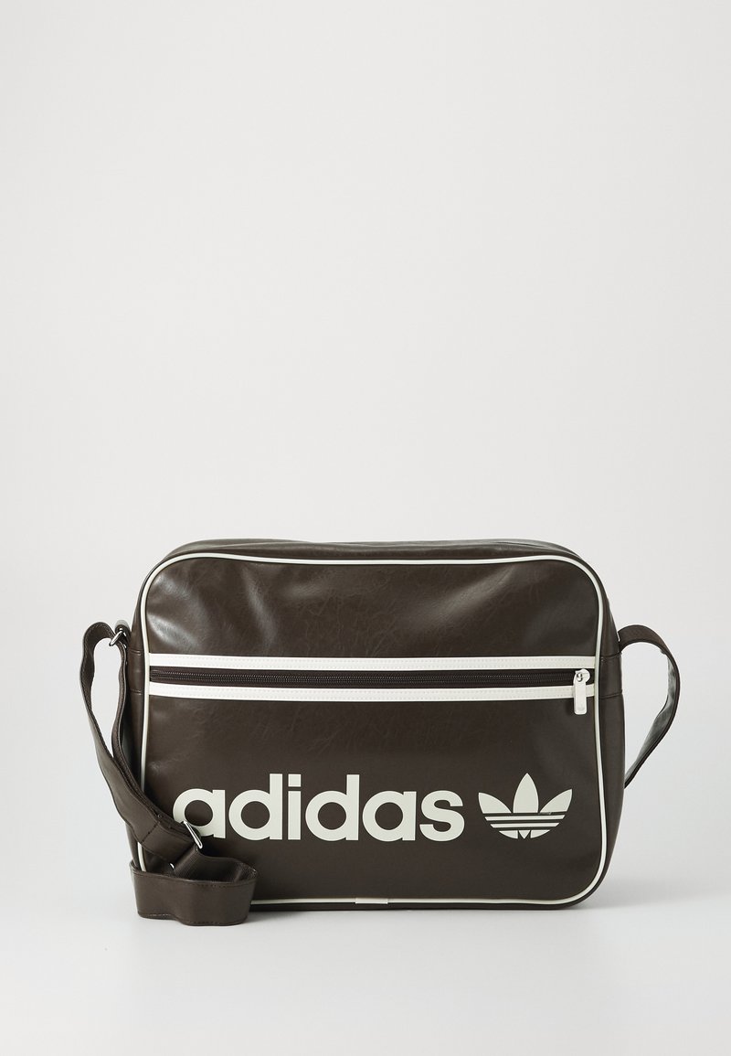 Mornjana vinilna torba za sporočila z belimi detajli, velikim sprednjim logotipom, zadrgo in nastavljivim trakom. Gladka tekstura z zaobljenimi robovi.